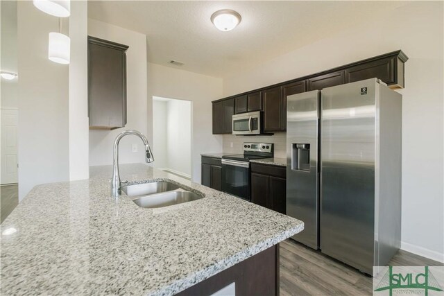 kitchen featuring kitchen peninsula, appliances with stainless steel finishes, light wood-type flooring, sink, and pendant lighting