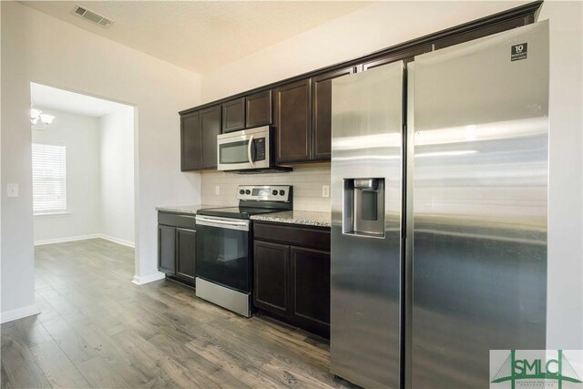 kitchen with a chandelier, appliances with stainless steel finishes, dark brown cabinets, and hardwood / wood-style floors