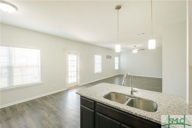 kitchen with pendant lighting, sink, ceiling fan, light stone countertops, and dark hardwood / wood-style flooring