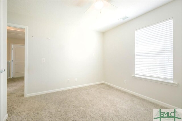 empty room featuring ceiling fan, light colored carpet, and a wealth of natural light