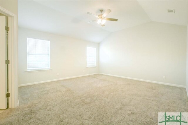 empty room featuring light colored carpet, vaulted ceiling, and ceiling fan