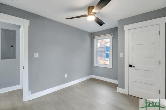 empty room featuring electric panel, light hardwood / wood-style flooring, and ceiling fan