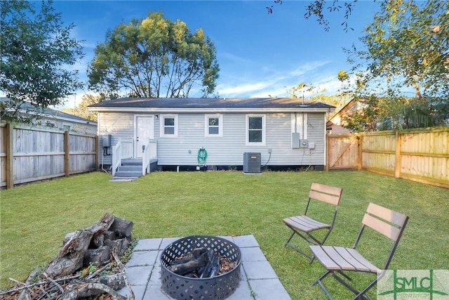 back of property featuring cooling unit, a yard, and an outdoor fire pit