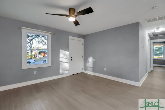 empty room featuring ceiling fan, a healthy amount of sunlight, and wood-type flooring