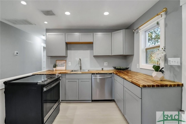 kitchen featuring stainless steel appliances, gray cabinetry, sink, and wooden counters