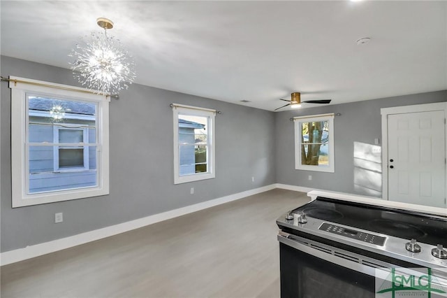 kitchen with pendant lighting, ceiling fan with notable chandelier, plenty of natural light, and stainless steel electric stove