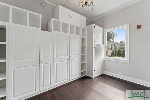 unfurnished bedroom featuring dark wood-style flooring, baseboards, a chandelier, and crown molding