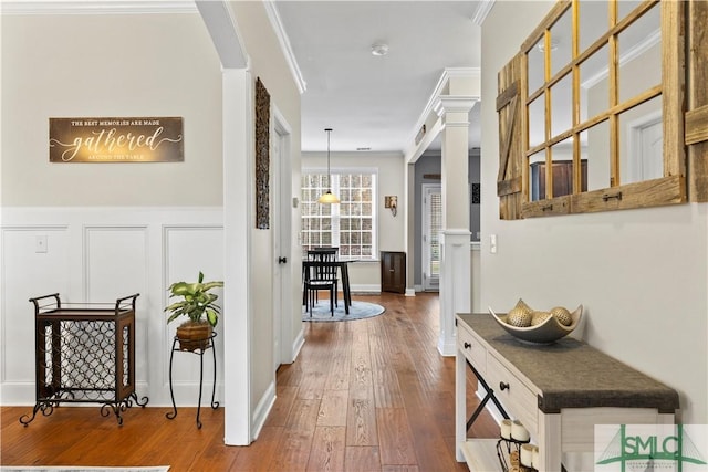 hallway with ornate columns, crown molding, and hardwood / wood-style floors