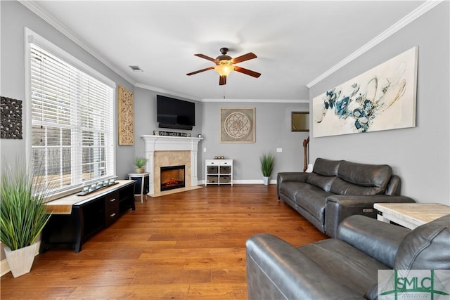 living room with hardwood / wood-style flooring, ceiling fan, ornamental molding, and a fireplace