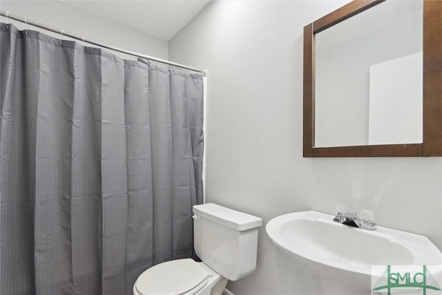 bathroom with curtained shower, toilet, and sink