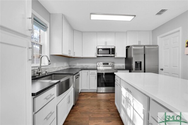 kitchen with white cabinets, appliances with stainless steel finishes, dark hardwood / wood-style flooring, and sink