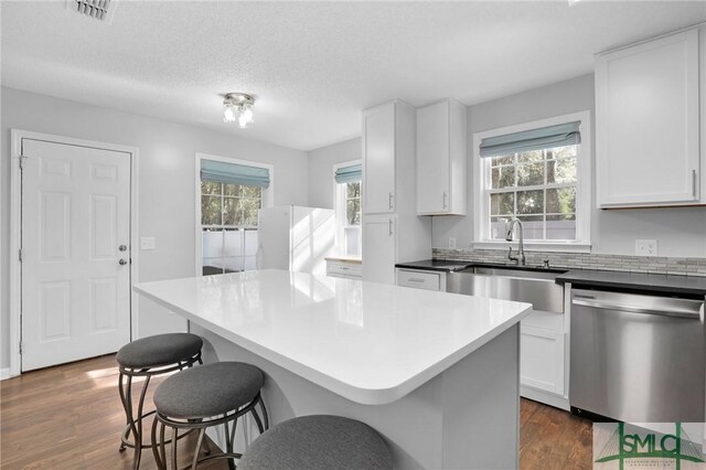 kitchen featuring white cabinetry, stainless steel dishwasher, a wealth of natural light, and sink