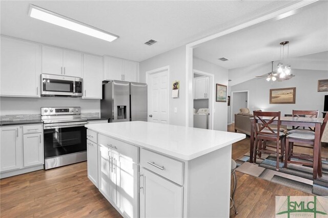 kitchen with pendant lighting, a center island, lofted ceiling, appliances with stainless steel finishes, and white cabinetry