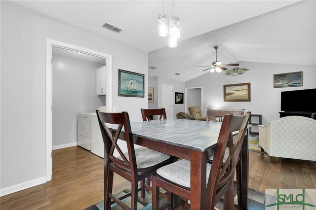 dining room featuring washer and clothes dryer, ceiling fan with notable chandelier, dark wood-type flooring, and vaulted ceiling