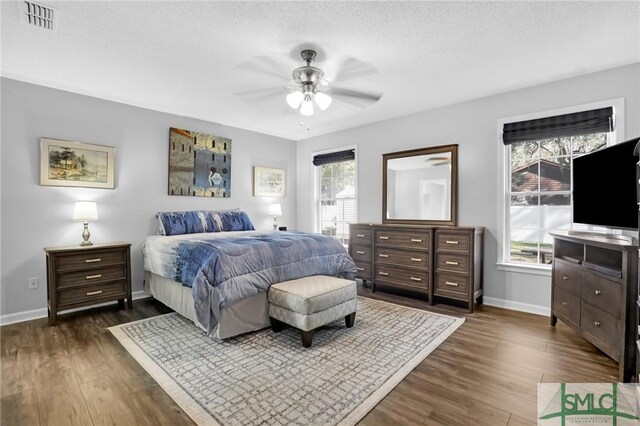 bedroom with ceiling fan, dark hardwood / wood-style floors, and a textured ceiling