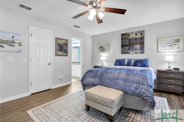 bedroom featuring ceiling fan, dark hardwood / wood-style flooring, and connected bathroom