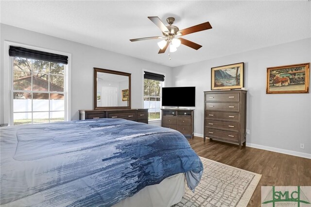 bedroom with ceiling fan, dark hardwood / wood-style floors, and multiple windows