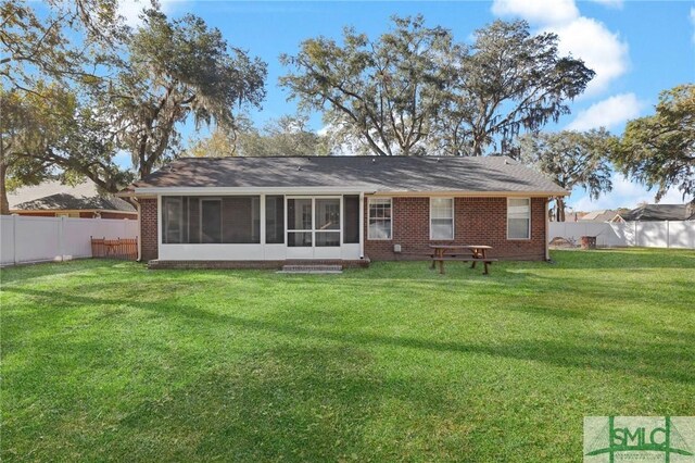 rear view of property with a sunroom and a yard