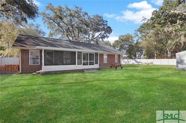 rear view of property featuring a lawn and a sunroom