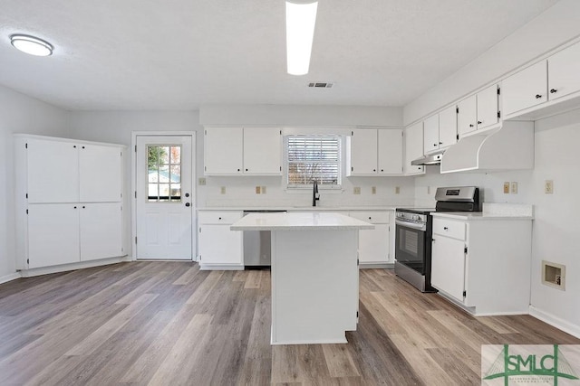 kitchen with white cabinetry, light hardwood / wood-style flooring, a kitchen island, and stainless steel appliances