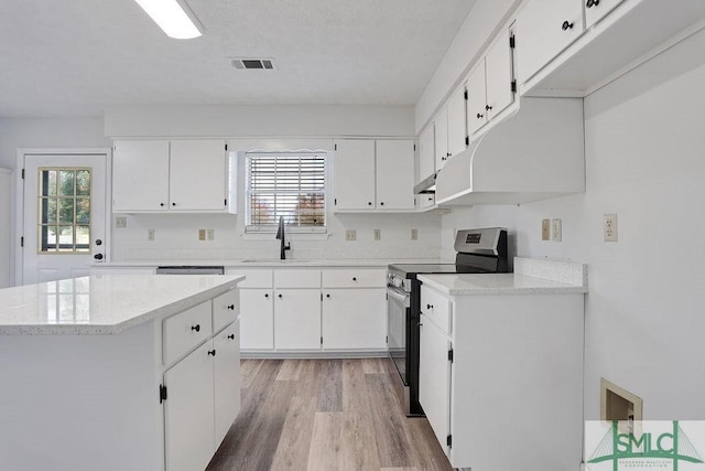 kitchen with white cabinets, light hardwood / wood-style floors, a wealth of natural light, and electric stove