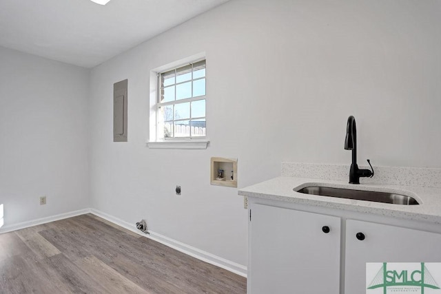 laundry room featuring cabinets, hookup for a washing machine, light wood-type flooring, sink, and electric panel