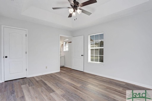 empty room featuring light hardwood / wood-style floors, a raised ceiling, and ceiling fan