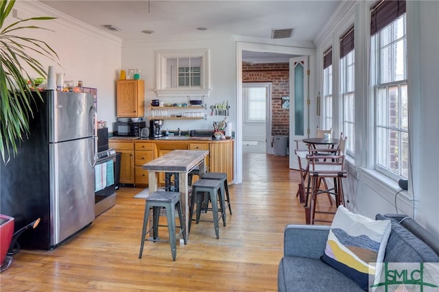 kitchen with plenty of natural light, ornamental molding, stainless steel appliances, and light hardwood / wood-style flooring