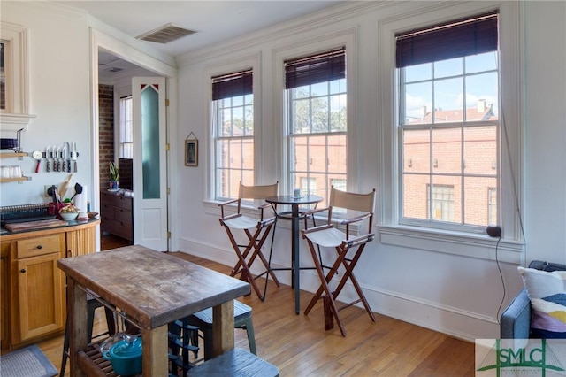 dining area with ornamental molding, a healthy amount of sunlight, and light hardwood / wood-style floors