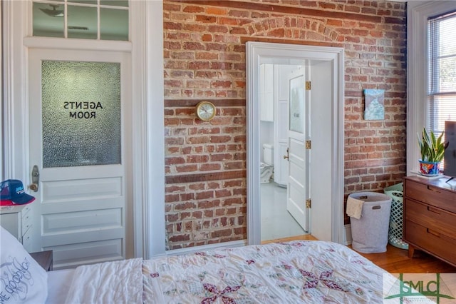 bedroom with light hardwood / wood-style flooring and brick wall