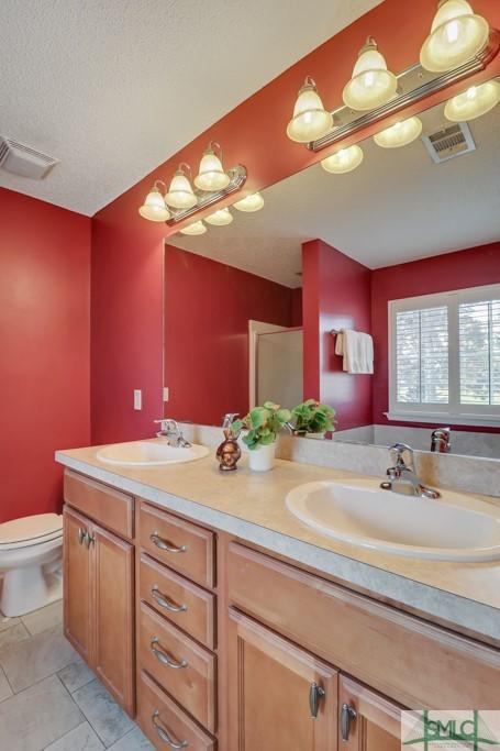 bathroom featuring tile patterned flooring, vanity, a textured ceiling, and toilet