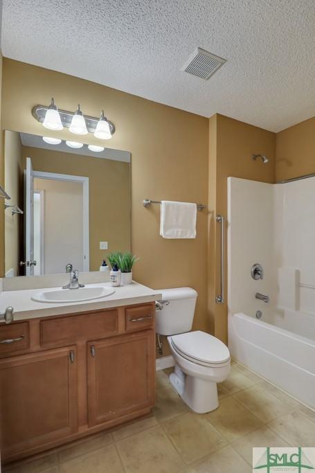 full bathroom featuring tile patterned flooring, a textured ceiling, and bathing tub / shower combination