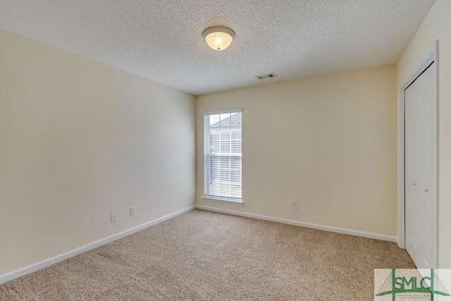 unfurnished bedroom with light colored carpet, a textured ceiling, and a closet