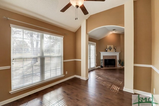 unfurnished living room featuring dark wood-type flooring, plenty of natural light, lofted ceiling, and ceiling fan