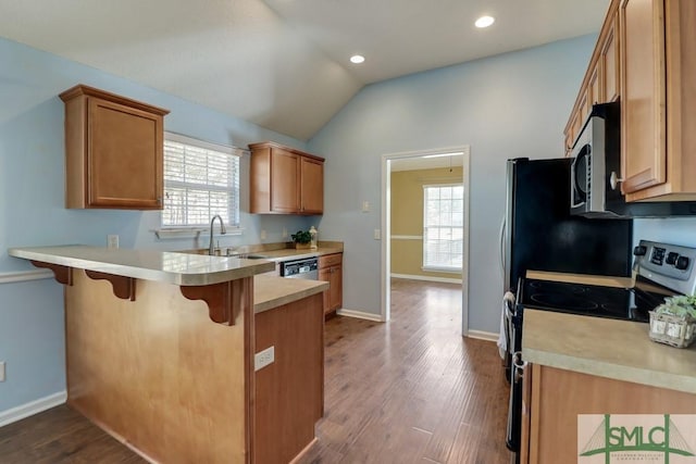 kitchen with a kitchen breakfast bar, sink, hardwood / wood-style floors, and appliances with stainless steel finishes