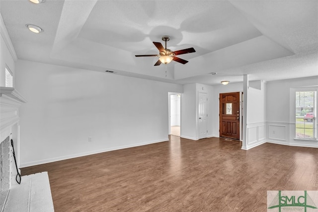 unfurnished living room with dark hardwood / wood-style floors, a textured ceiling, and a tray ceiling