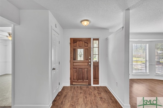 foyer featuring ceiling fan, wood-type flooring, and a textured ceiling