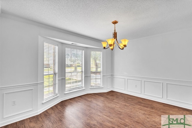 unfurnished dining area with ornamental molding, wood-type flooring, a textured ceiling, and a notable chandelier