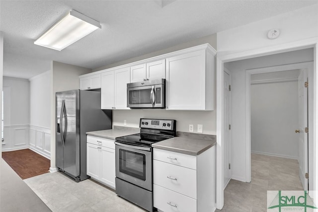 kitchen with white cabinets, a textured ceiling, and stainless steel appliances