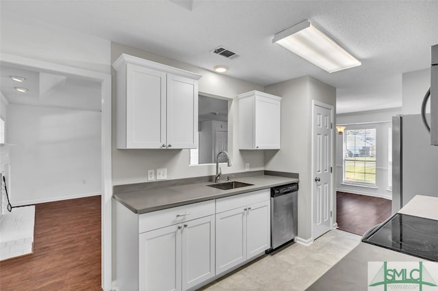 kitchen featuring appliances with stainless steel finishes, a textured ceiling, sink, light hardwood / wood-style flooring, and white cabinetry