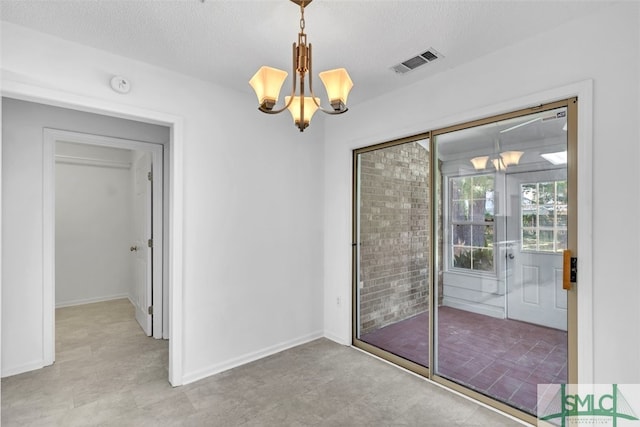 unfurnished room with a textured ceiling and an inviting chandelier