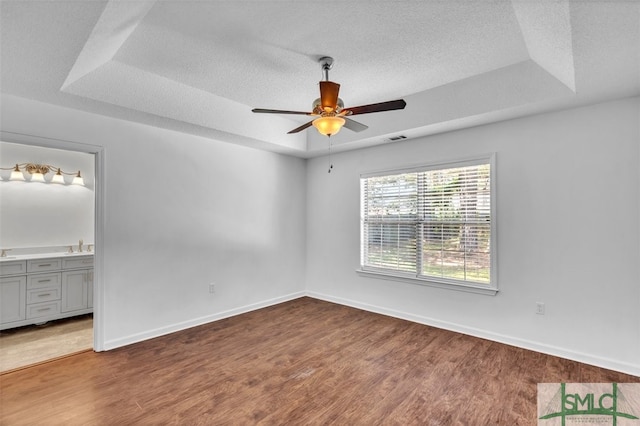 spare room featuring a tray ceiling, ceiling fan, and hardwood / wood-style flooring