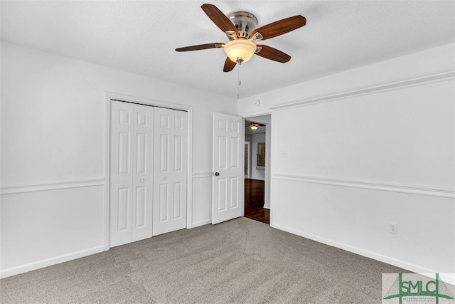 unfurnished bedroom with carpet flooring, ceiling fan, a textured ceiling, and a closet