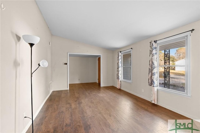 empty room with dark hardwood / wood-style floors and vaulted ceiling