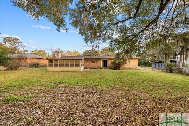 rear view of property with a lawn and a sunroom