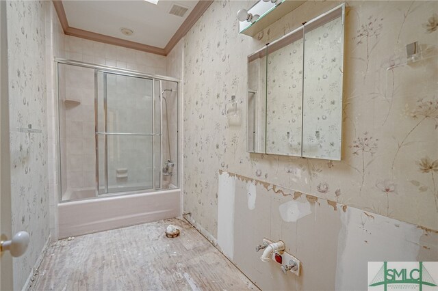 bathroom with crown molding and bath / shower combo with glass door