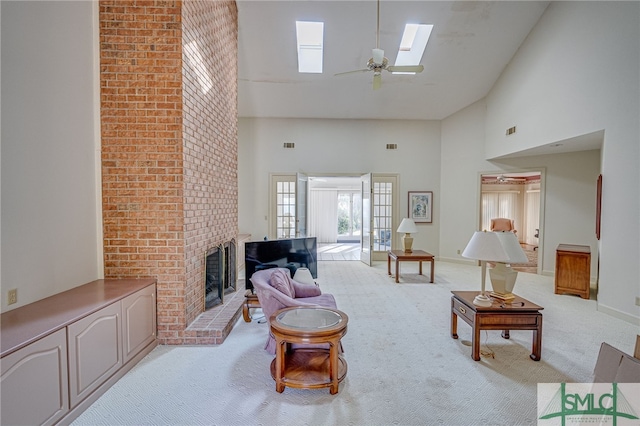 carpeted living room with a skylight, ceiling fan, a towering ceiling, and a brick fireplace