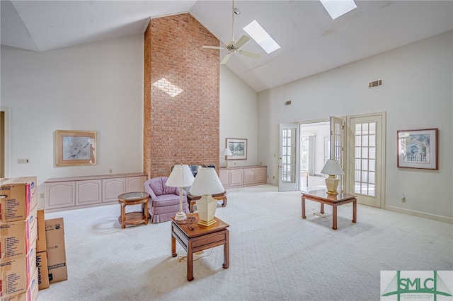 living room featuring a skylight, light carpet, high vaulted ceiling, and ceiling fan