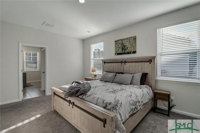 bedroom with ensuite bathroom, light carpet, and multiple windows