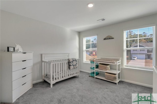 carpeted bedroom featuring a nursery area and multiple windows